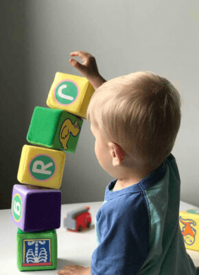 Toddler stacking colorful soft blocks while playing at a kindergarten activity table